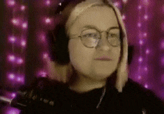 a woman wearing headphones and glasses is looking at the camera .