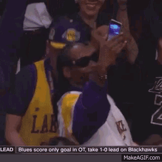 a man in a lakers jersey is cheering with his arms in the air