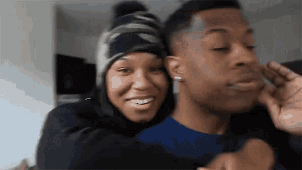 a man and a woman are hugging each other and the woman is wearing a hat