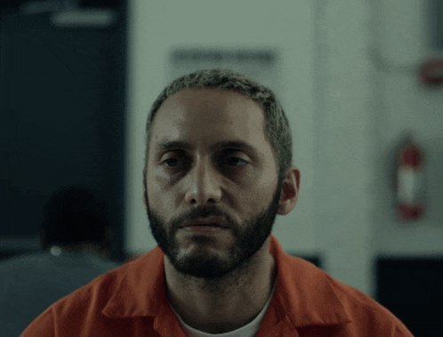a man with a beard is wearing an orange uniform