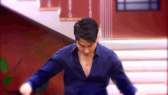 a man in a blue shirt is standing in front of stairs