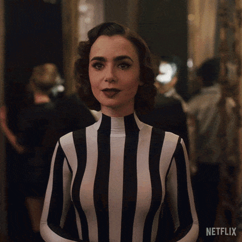 a woman in a black and white striped outfit is standing in front of a netflix sign