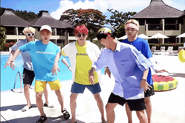 a group of young men are standing in front of a pool and one of them has a shirt that says quicksilver on it