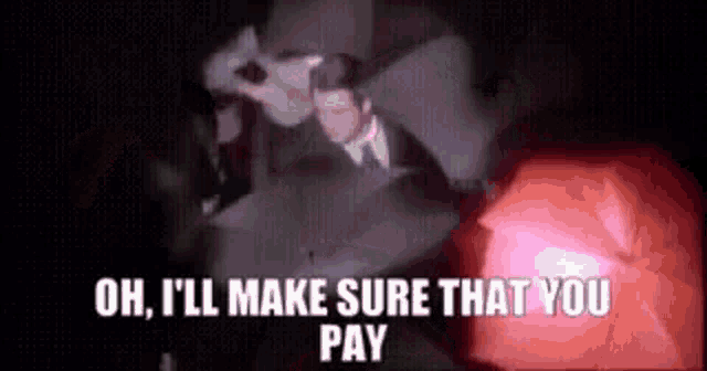 a man in a suit and tie is standing in the dark with a red light behind him .