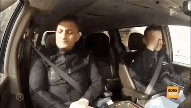 two men are sitting in the back seat of a car with the number 12 on the screen