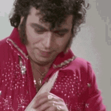a man in a red suit is holding a piece of paper in his hands .