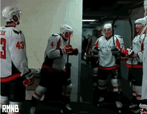 a group of hockey players are standing in a locker room and one has the number 43 on his jersey
