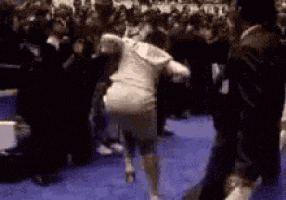 a woman is running in front of a crowd of people on a blue carpet .