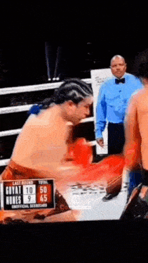 a man in a boxing ring with a referee watching .