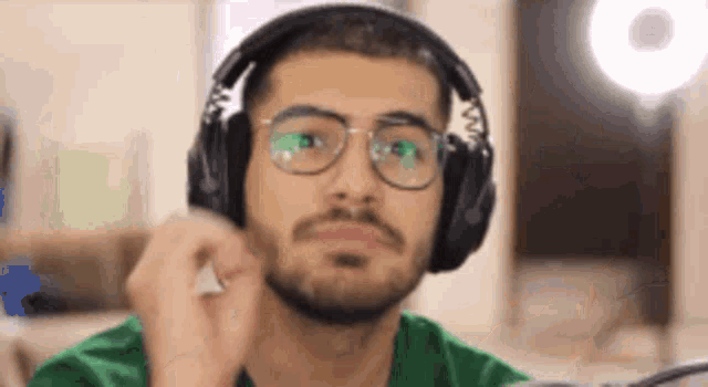 a man wearing headphones and glasses is looking at the camera .