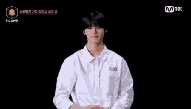 a young man wearing a white shirt is sitting in front of a black background .