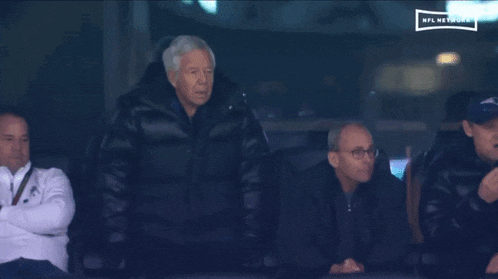 a group of men sit in a stadium watching a game on the nfl network