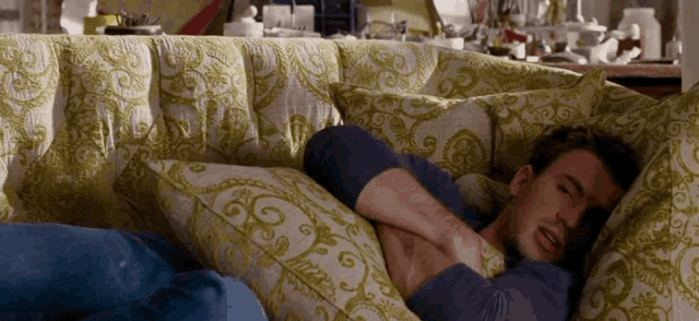 a man laying on a couch with a pillow on his chest that says ' swirls ' on it