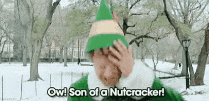 a man in a green elf hat is covering his face with his hand in a park .