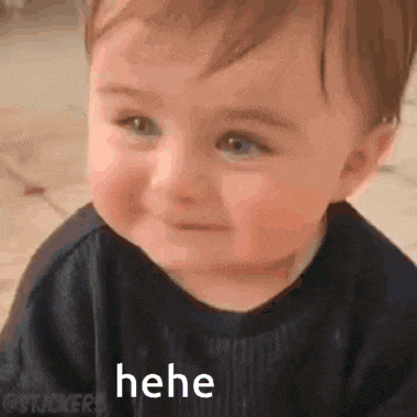 a baby is smiling and making a funny face while laying on the floor .