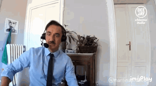 a man in a blue shirt and tie is wearing headphones and a microphone