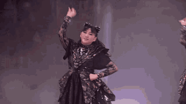 a woman in a black dress is dancing on stage
