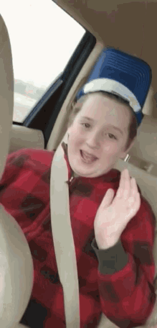 a young girl wearing a blue hat is sitting in the back seat of a car ..