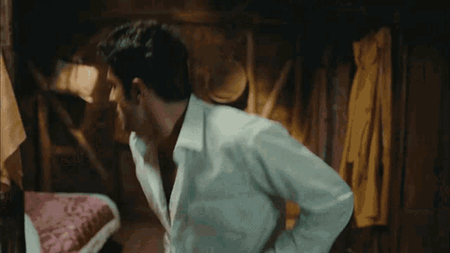 a man in a white shirt is standing in a dark room with his hands on his hips