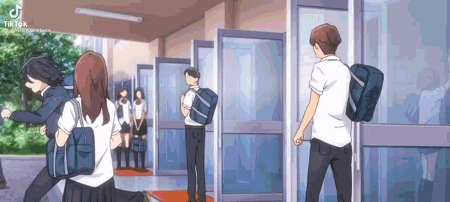 a group of students are walking through a hallway in a school building .