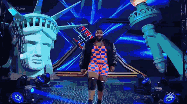 a statue of liberty is behind a wrestler in a colorful outfit
