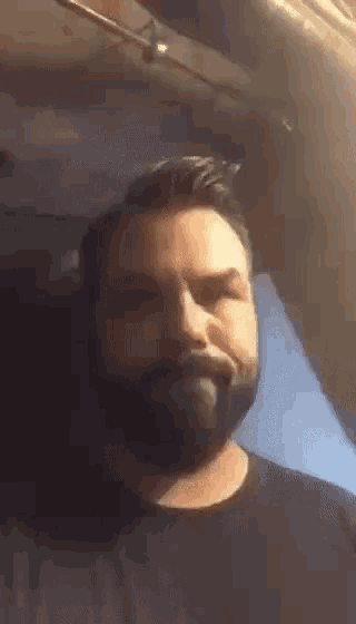 a man with a beard is making a funny face while wearing a black shirt