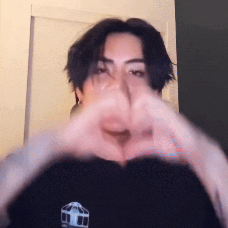 a close up of a person making a heart shape with their hands .