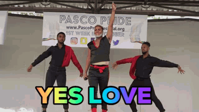 a group of people dancing in front of a banner that says yes love