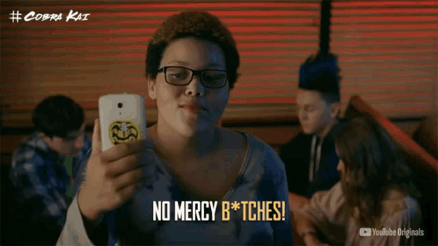 a person holding a cell phone with the words no mercy b * tches on it