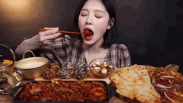a woman is eating a tray of food with chopsticks ..