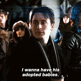 a man in a black coat and scarf is talking about adopted babies .
