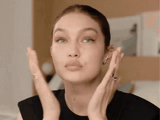 a close up of a woman 's face with her hands in front of her face