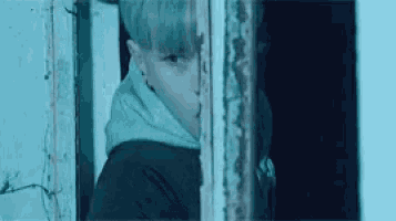 a young boy is peeking out of a doorway .