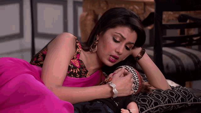 a woman is laying on a bed with a doll