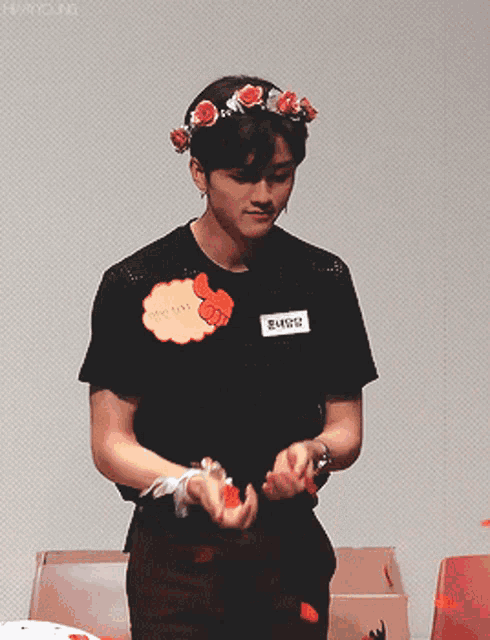 a young man wearing a flower crown and a black shirt with a name tag that says 2 - chen2
