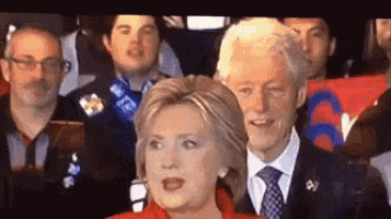 hillary clinton is giving a speech in front of a crowd of people .