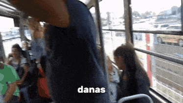 a man and a woman are riding a bus with the word danas on the bottom .