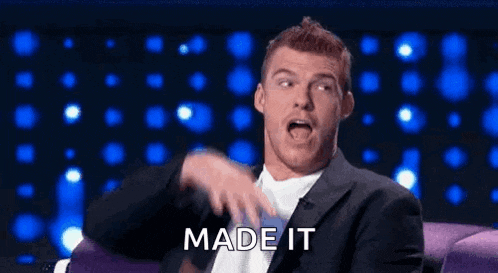 a man in a suit is sitting in a chair and making a funny face with the words made it behind him .