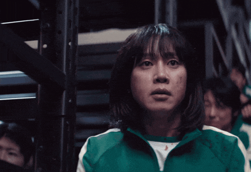 a woman in a green shirt is standing in a dark room with other people