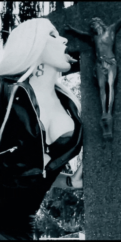 a woman sticking her tongue out in front of a statue of jesus on a cross