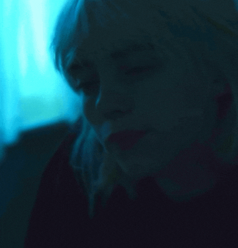 a close up of a woman 's face in the dark with a blue background