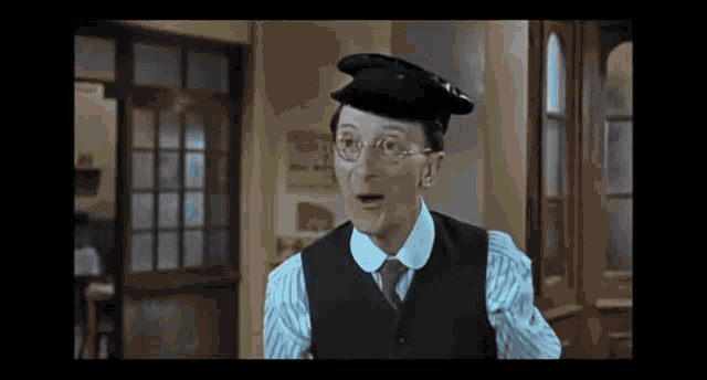 a man wearing glasses and a hat is making a funny face