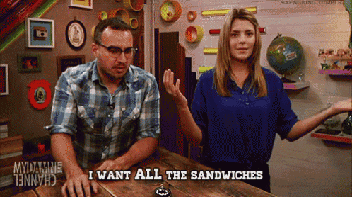 a man and a woman sitting at a table with the words i want all the sandwiches on the table