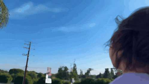 a blurry picture of a person looking up at a blue sky with a palm tree in the background