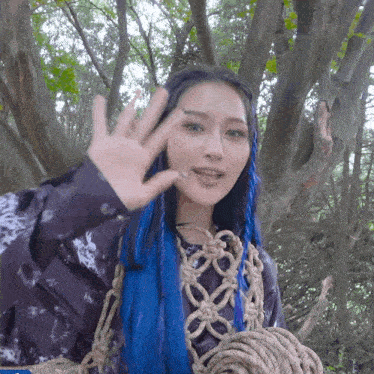 a woman with blue hair is waving her hand