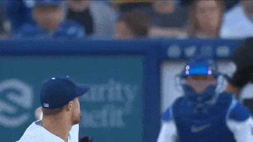 a blurred image of a baseball player and catcher with a security sign in the background