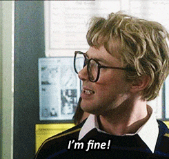 a man wearing glasses says " i 'm fine " in front of a bulletin board