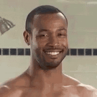 a shirtless man is smiling in a shower while taking a shower .