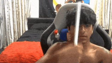a man without a shirt is sitting in a chair with a nos can in front of his face