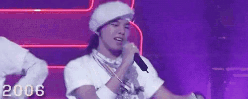 a man in a white hat is singing into a microphone on stage .
